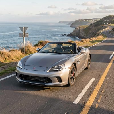 a convertible sports car on a coastal road, no license plate