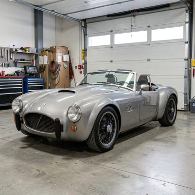 a two seater roadster in a garage, no license plate