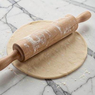 a rolling pin flattening pastry on marble