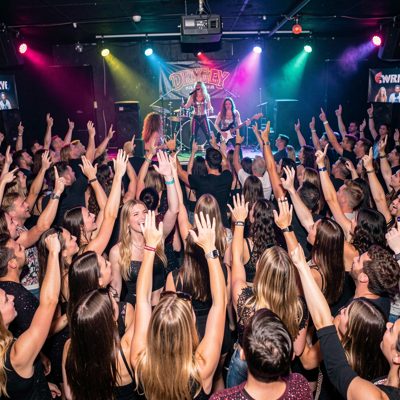 a crowd cheering at a drag show in a nightclub