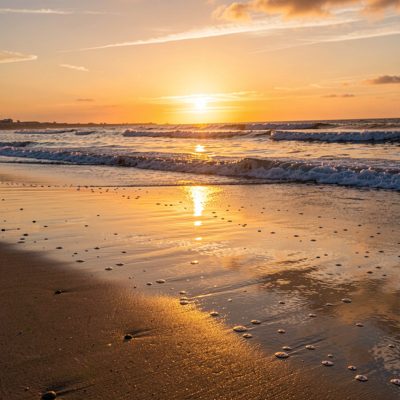 a sunrise reflected in wet sand