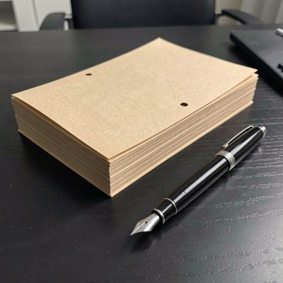 a stack of manila folders and a fountain pen on a dark desk