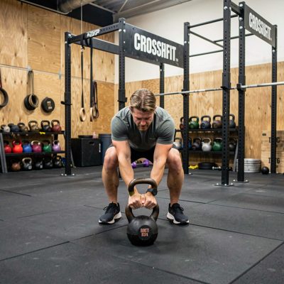 crossfit box showing kettlebell swings over mat surface
