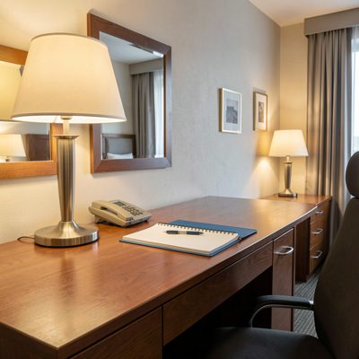 a hotel room desk with a lamp and notepad