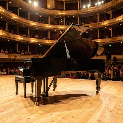 a grand piano on a concert hall stage under warm lights