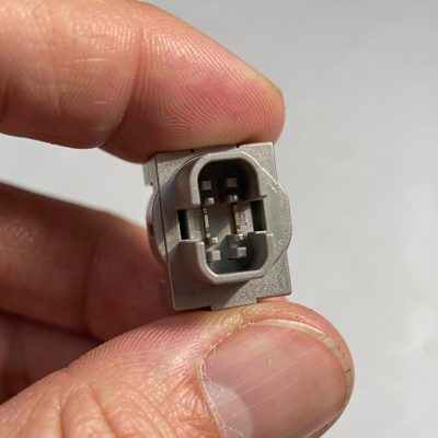 an lc duplex fibre connector held between fingertips