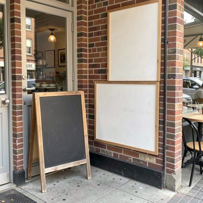 a corner cafe with a blank chalkboard by the door, blank empty sign board, no text, no lettering, no logo