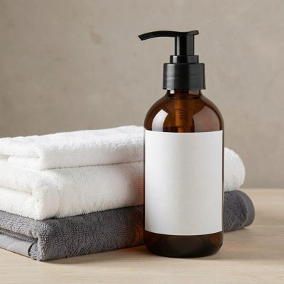 a pump bottle beside folded towels with a blank white label