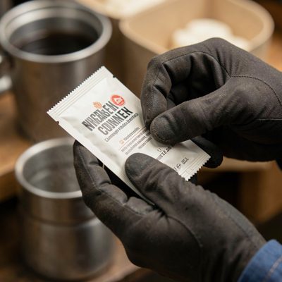 a pair of gloved hands opening a sachet