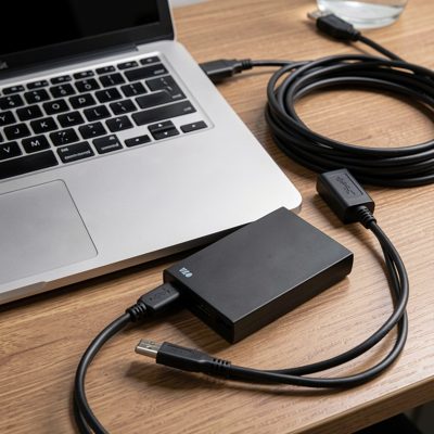 a laptop and external drive on a desk with cables coiled