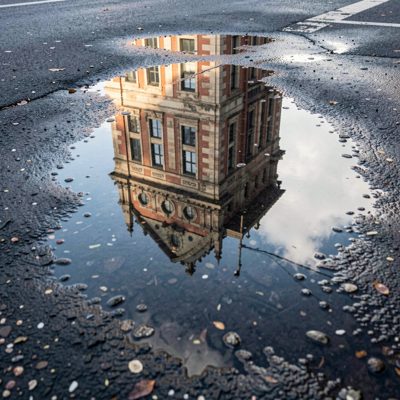 a puddle reflecting a building above