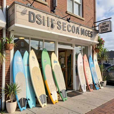 a surf shop front with boards leaning outside