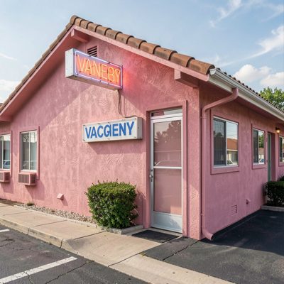 a pink stucco motel with a neon vacancy sign
