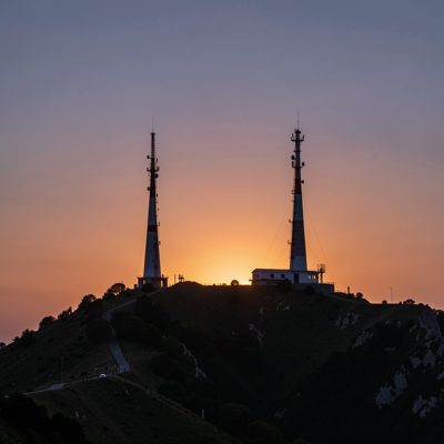 two hilltop masts silhouetted against a dusk sky
